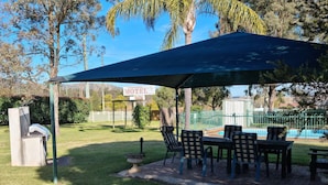 A covered outdoor seating area with a pool in the background.