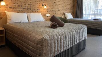 Habitación de hotel con dos camas, una pared de ladrillo y una ventana con cortinas.