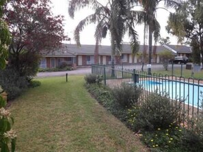 Un barrio residencial con piscina, patio cercado y varias casas al fondo.