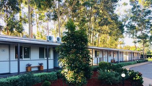 En rad byggnader i motelstil med en välanlagd trädgård som har ett stort träd i mitten och en cirkelformad stenformation.