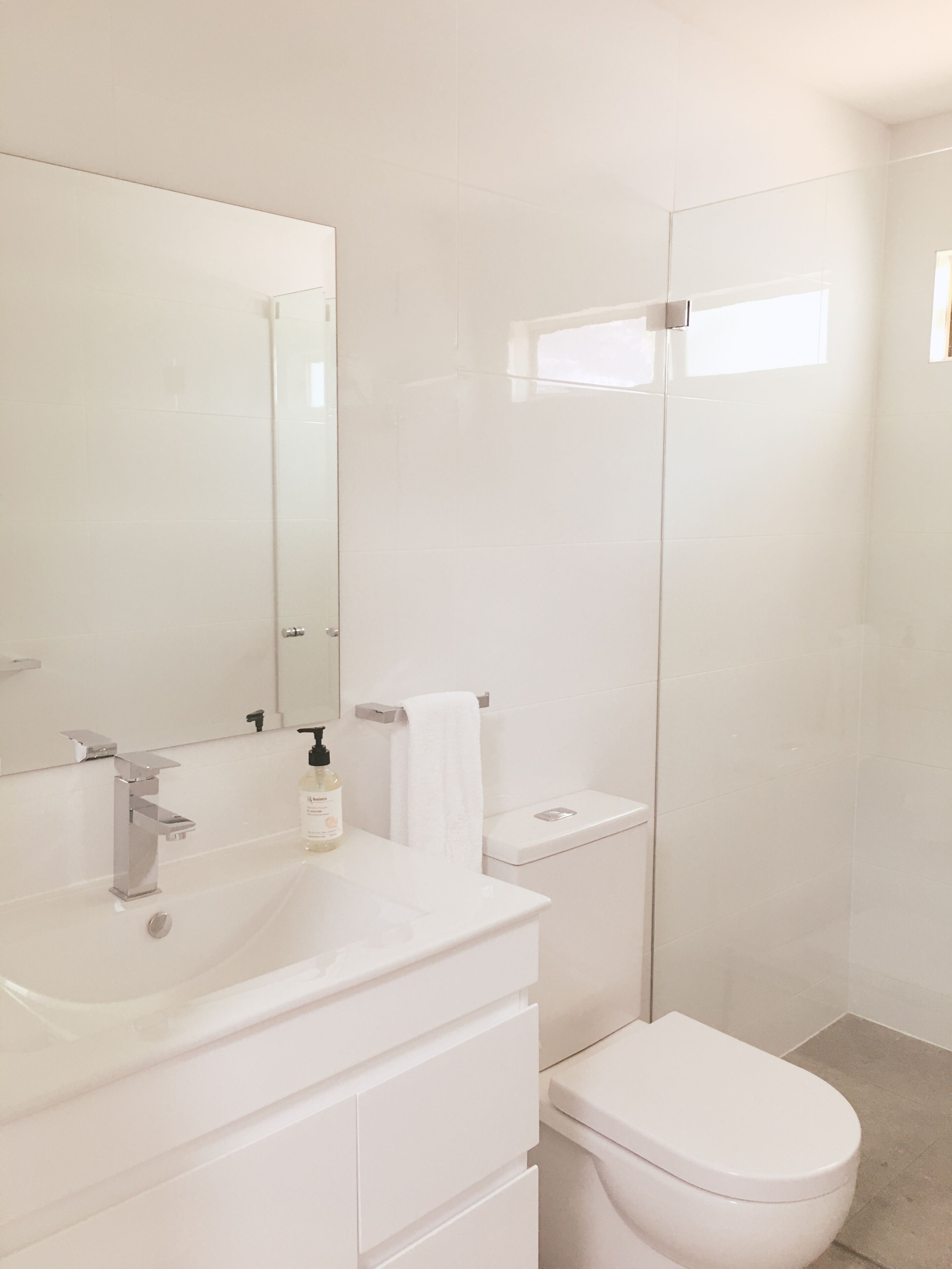 A modern bathroom with a white sink, mirror, and toilet.