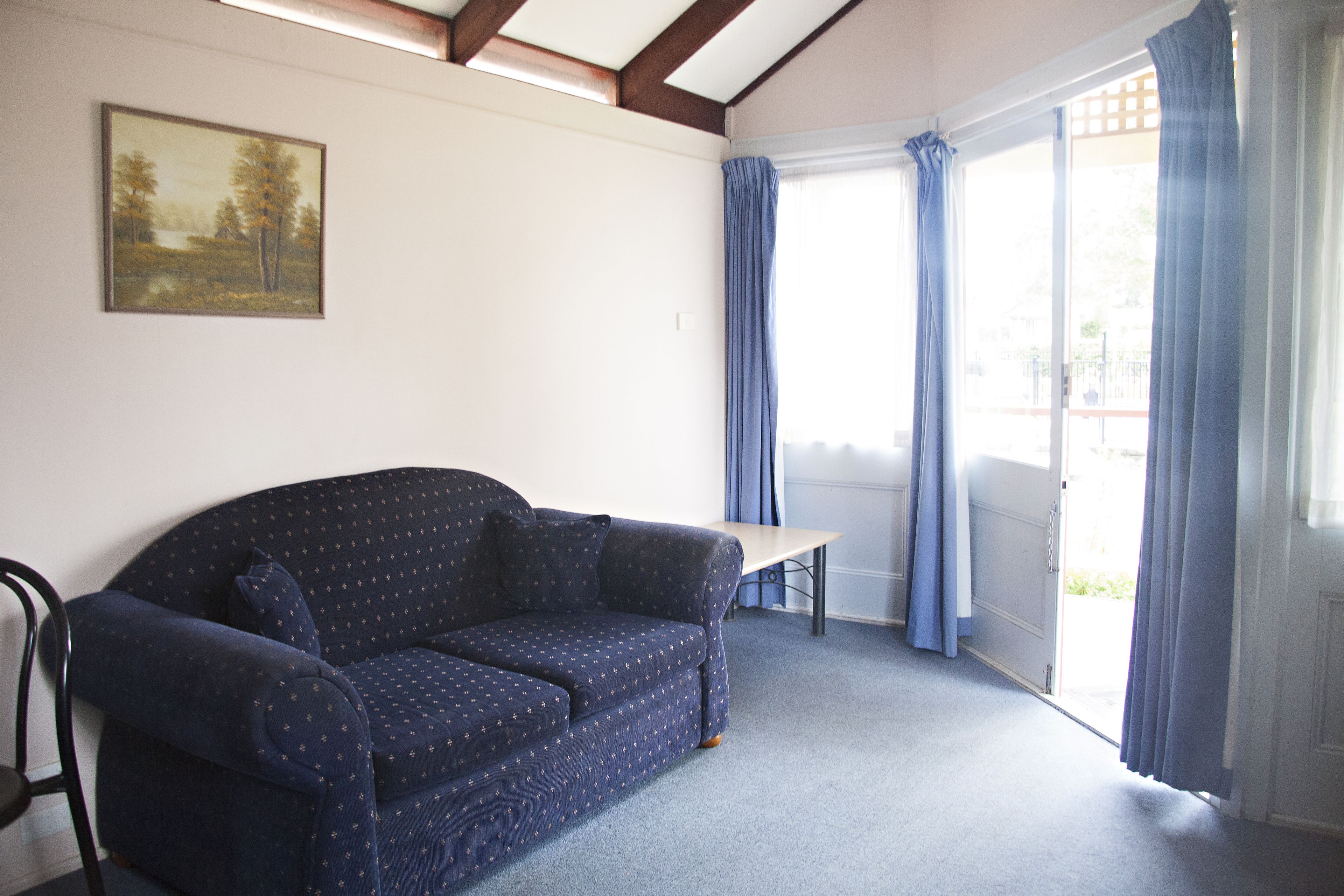 A room with a dark blue sofa, a small table, and a painting on the wall.