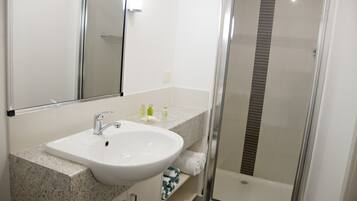 A bathroom with a white sink, a mirror, and a glass shower enclosure.