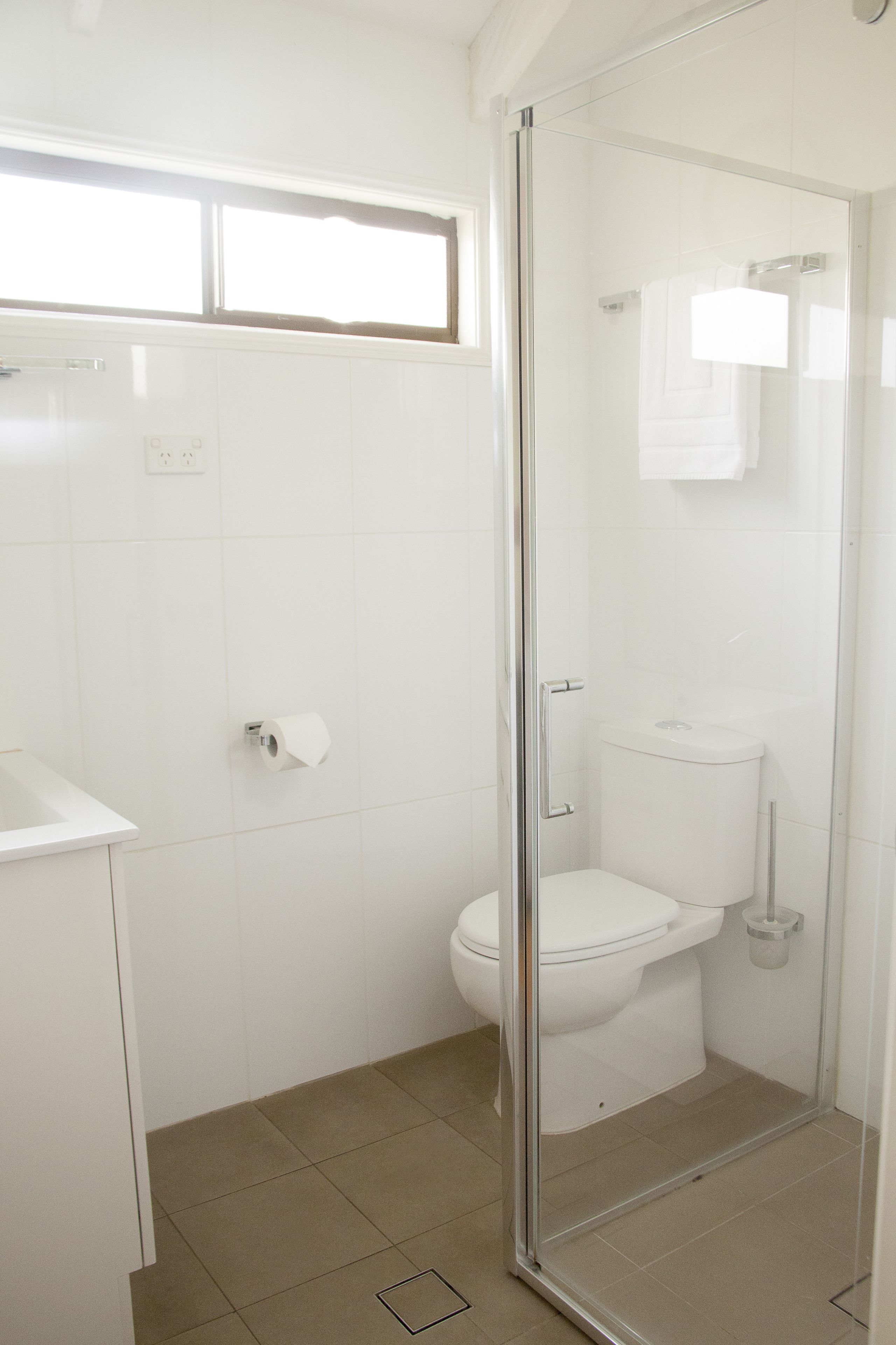 A bathroom with a toilet, a shower enclosure, and a sink.