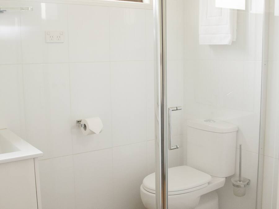 Un baño con inodoro, cabina de ducha y lavamanos.