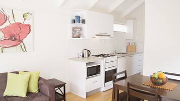 Una cocina moderna con armarios blancos, una mesa de comedor con sillas y un sofá con cojines.