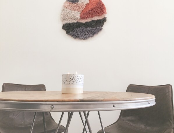 A round dining table with a white candle on it, surrounded by leather chairs.