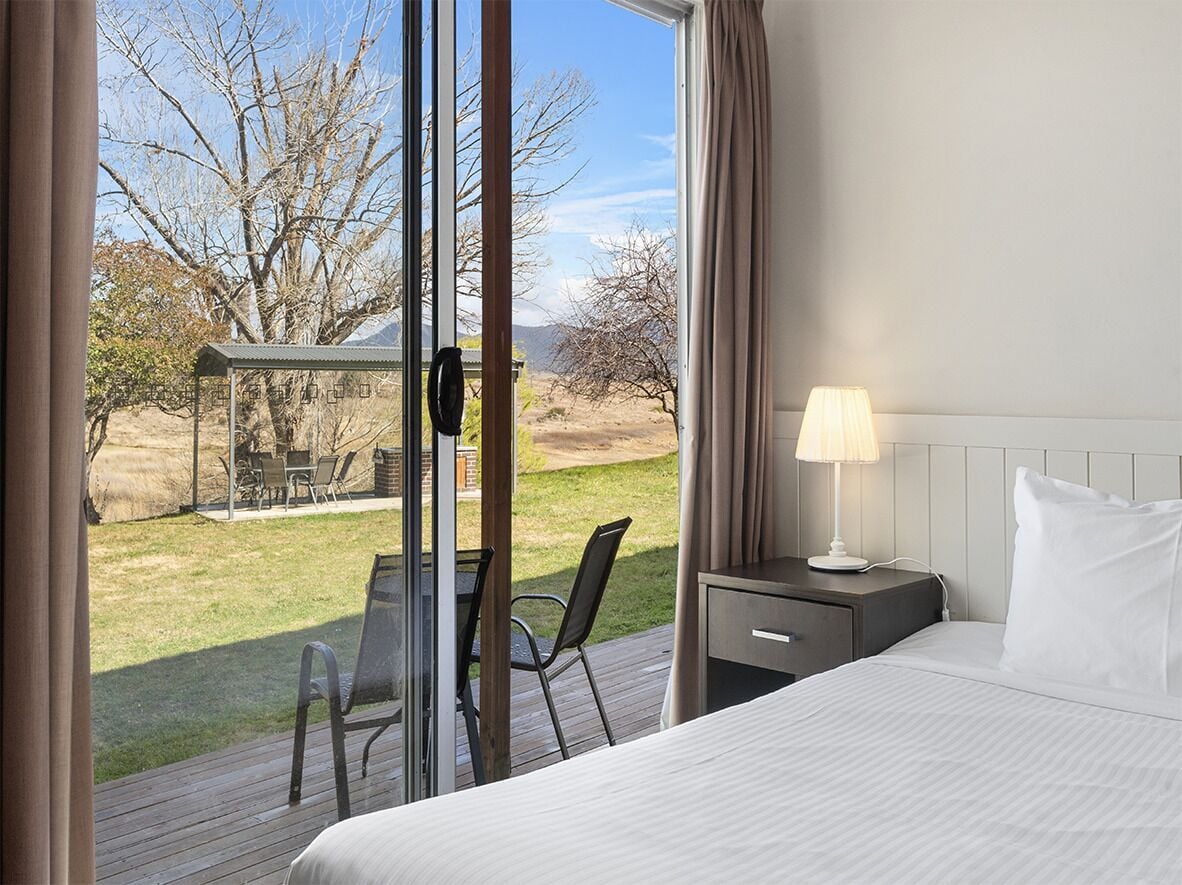 Een hotelkamer met een bed, een bureau, een stoel en uitzicht op het groen.