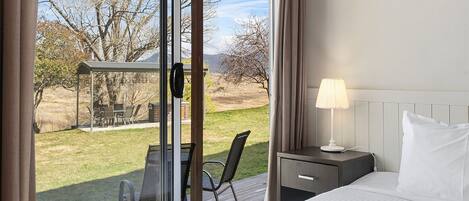 Een hotelkamer met een bed, een bureau, een stoel en uitzicht op het groen.