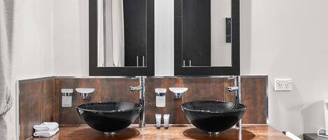 A bathroom with two black vessel sinks, a wooden vanity, and a large mirror above the sinks.