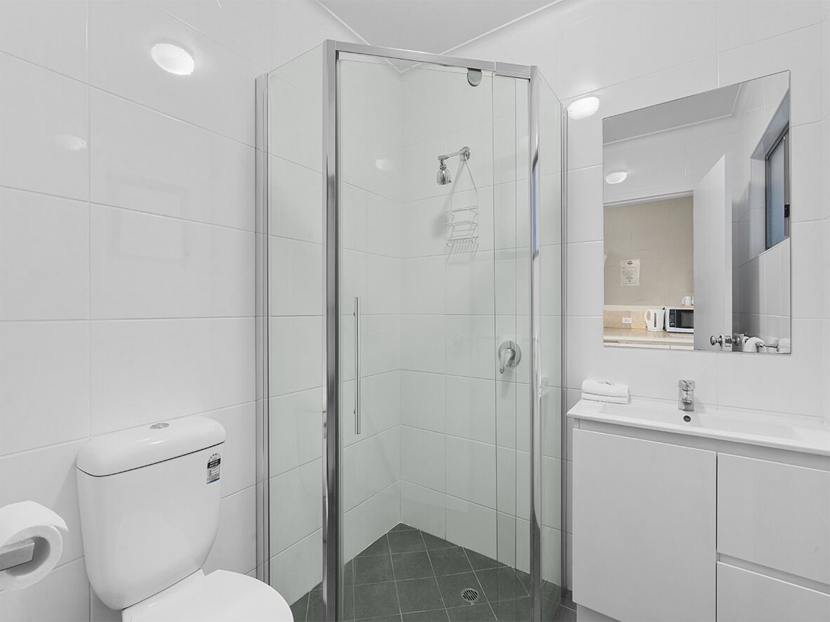 A modern bathroom with a glass-enclosed shower, a toilet, and a sink with a mirror above it.