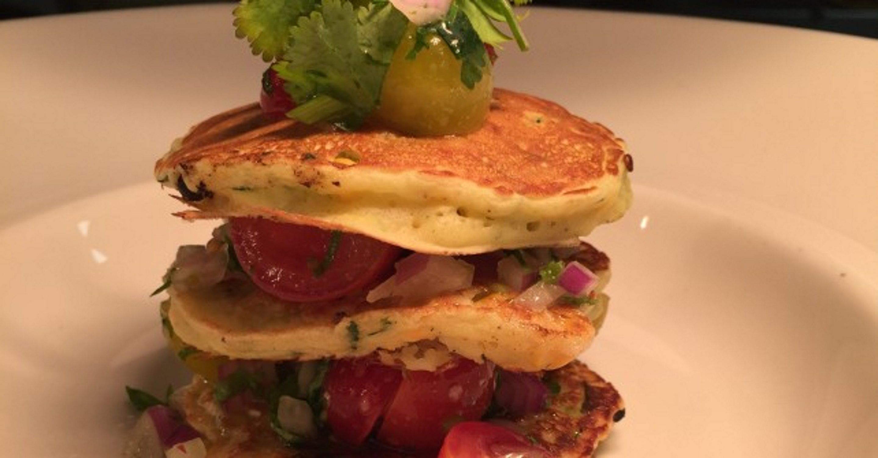 A stack of pancakes with a garnish on top.