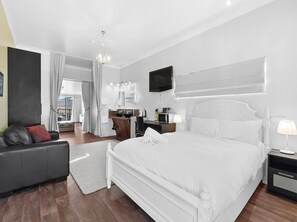 A modern bedroom with a large bed, a sofa, a TV, and a desk. - Siesta Villa (East Jindabyne)
