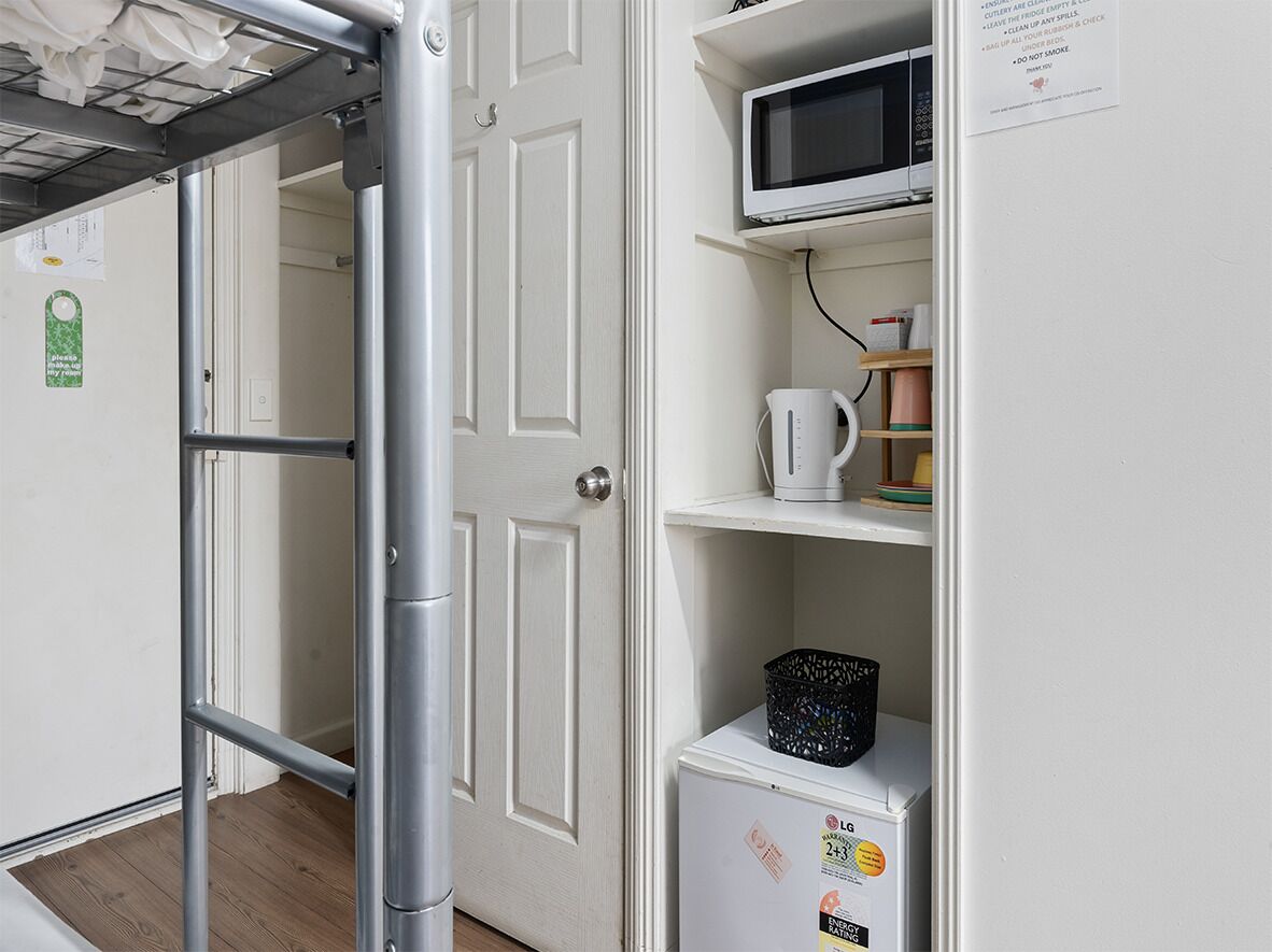 A compact kitchen with a microwave, kettle, and a small refrigerator.