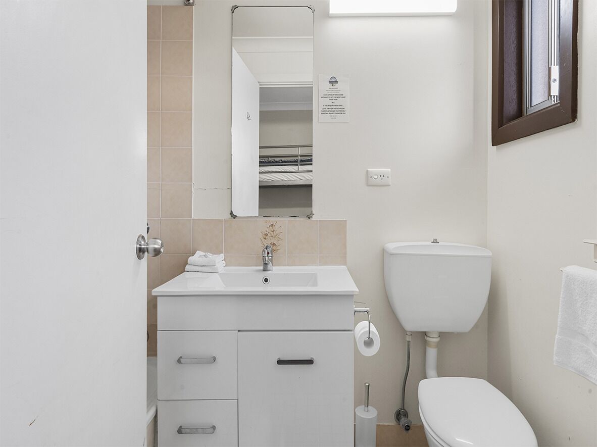 Een badkamer met een wit wastafelmeubel, spiegel, toilet en handdoekhouder.