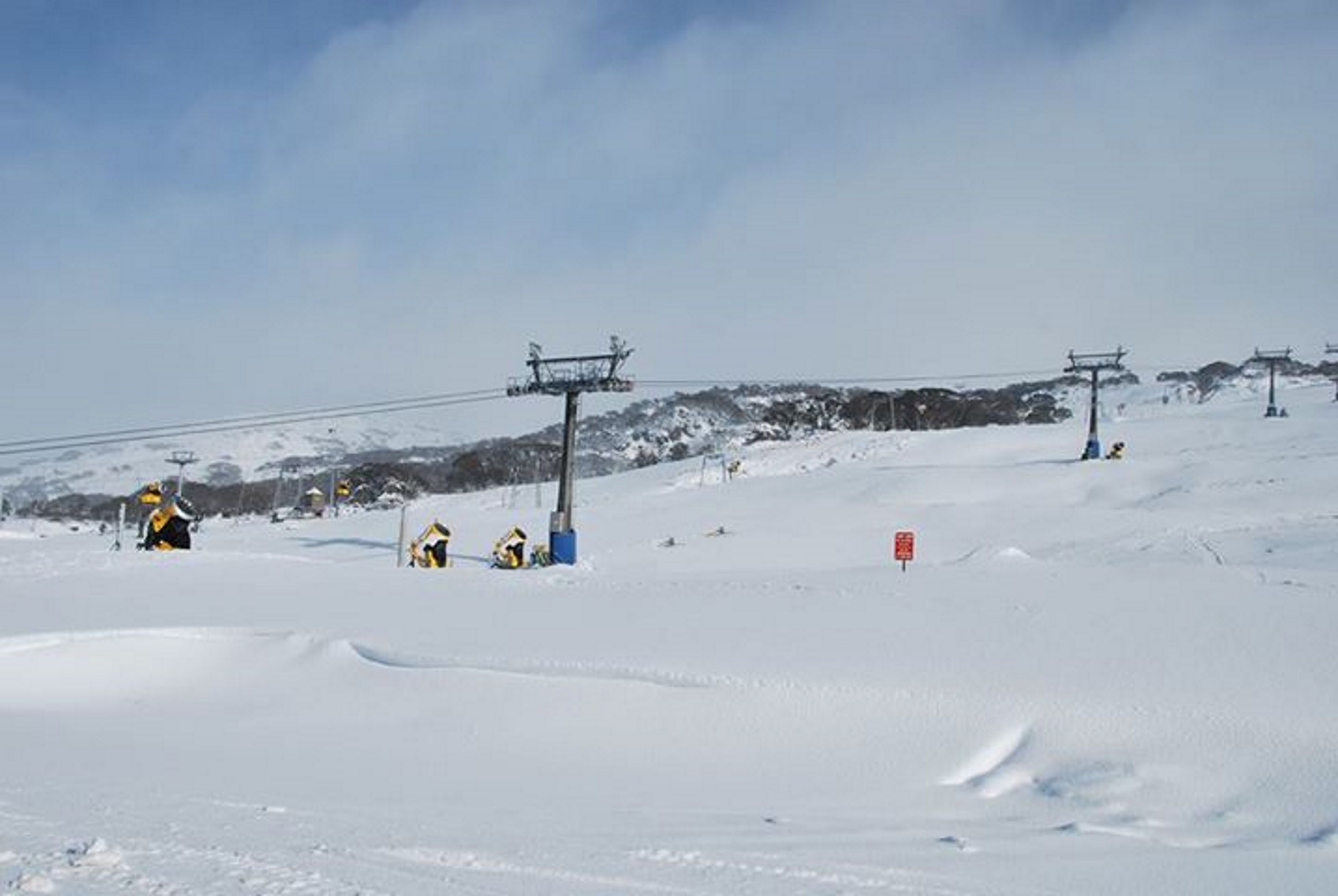 Una pista de esquí nevada con telesillas y cielo despejado.