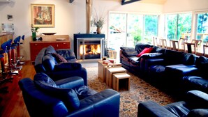 A modern living room with a fireplace, leather sofas, and a dining area with chairs and a table. - Blue Lake Lodge (Arthurs Lake)