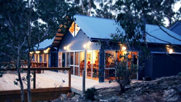 A modern building with a wooden deck and glass doors, surrounded by trees. - Blue Lake Lodge (Arthurs Lake)