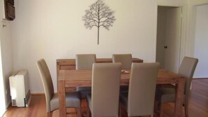 A dining area with a wooden table and six chairs. - Yarra Glen Racecourse Apartments (Yarra Glen)