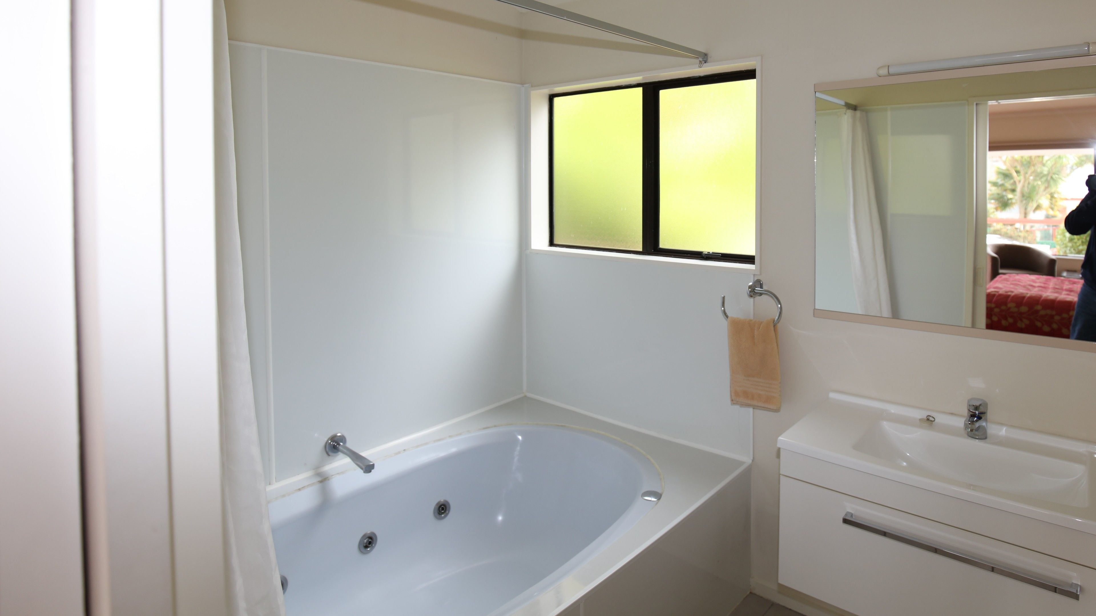 A bathroom with a bathtub, a sink, and a window.