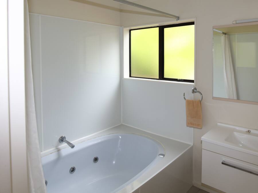 A bathroom with a bathtub, a sink, and a window.
