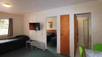 A room with two beds, a TV, a heater, and a window with curtains.