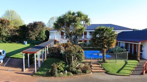 A hotel with a parking area, a covered walkway, and a swimming pool. - Bk's Counties Motor Lodge (Pukekohe)