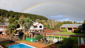 A residential area with a swimming pool, covered patio, and houses with red roofs. - Bk's Counties Motor Lodge (Pukekohe)