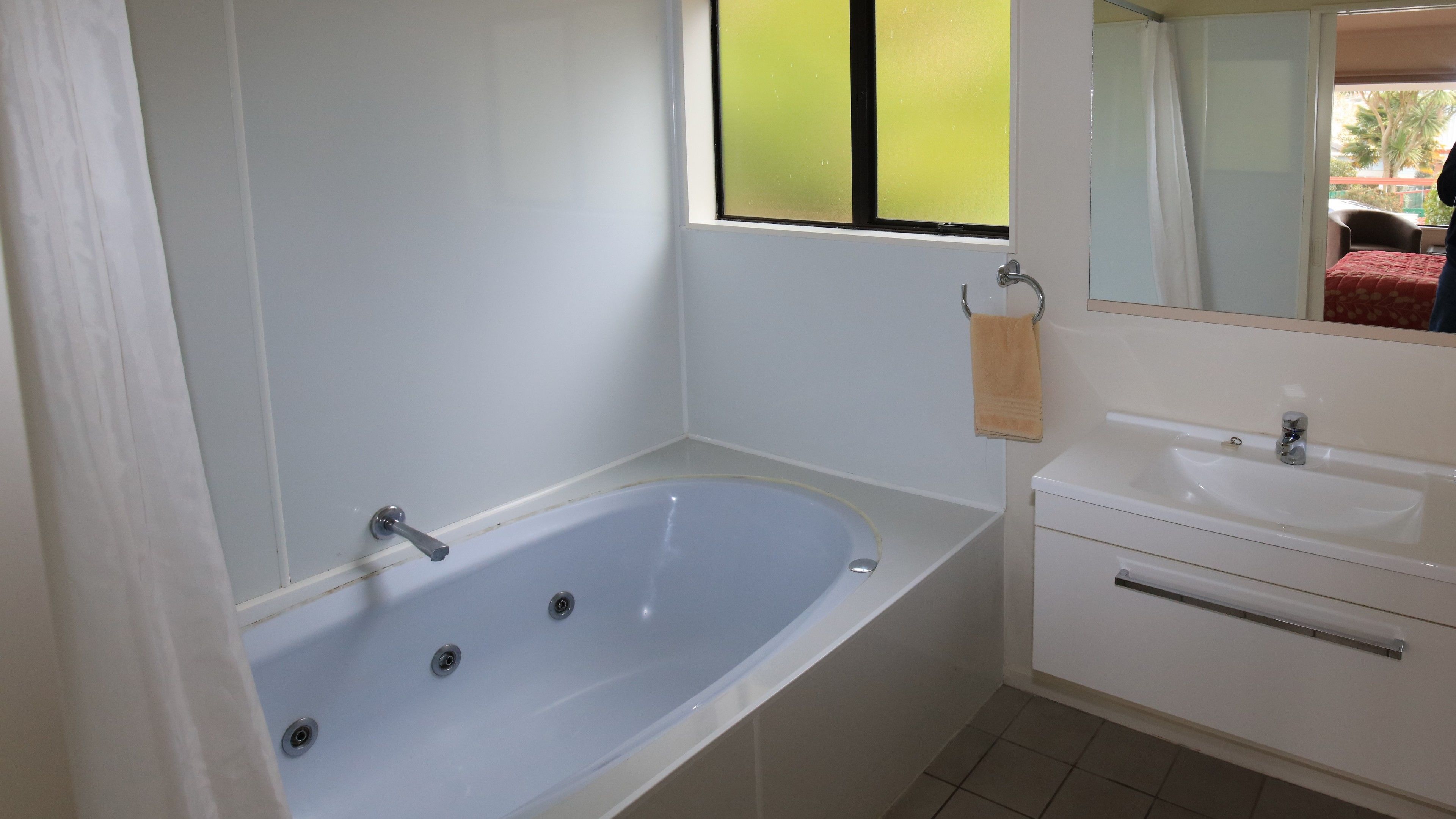 Un baño con bañera, lavamanos y espejo.