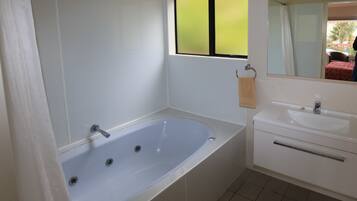 A bathroom with a bathtub, a sink, and a mirror.