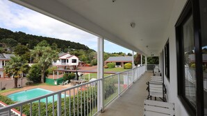 A balcony with a view of a swimming pool, a house, and a hilly landscape. - Bk's Counties Motor Lodge (Pukekohe)