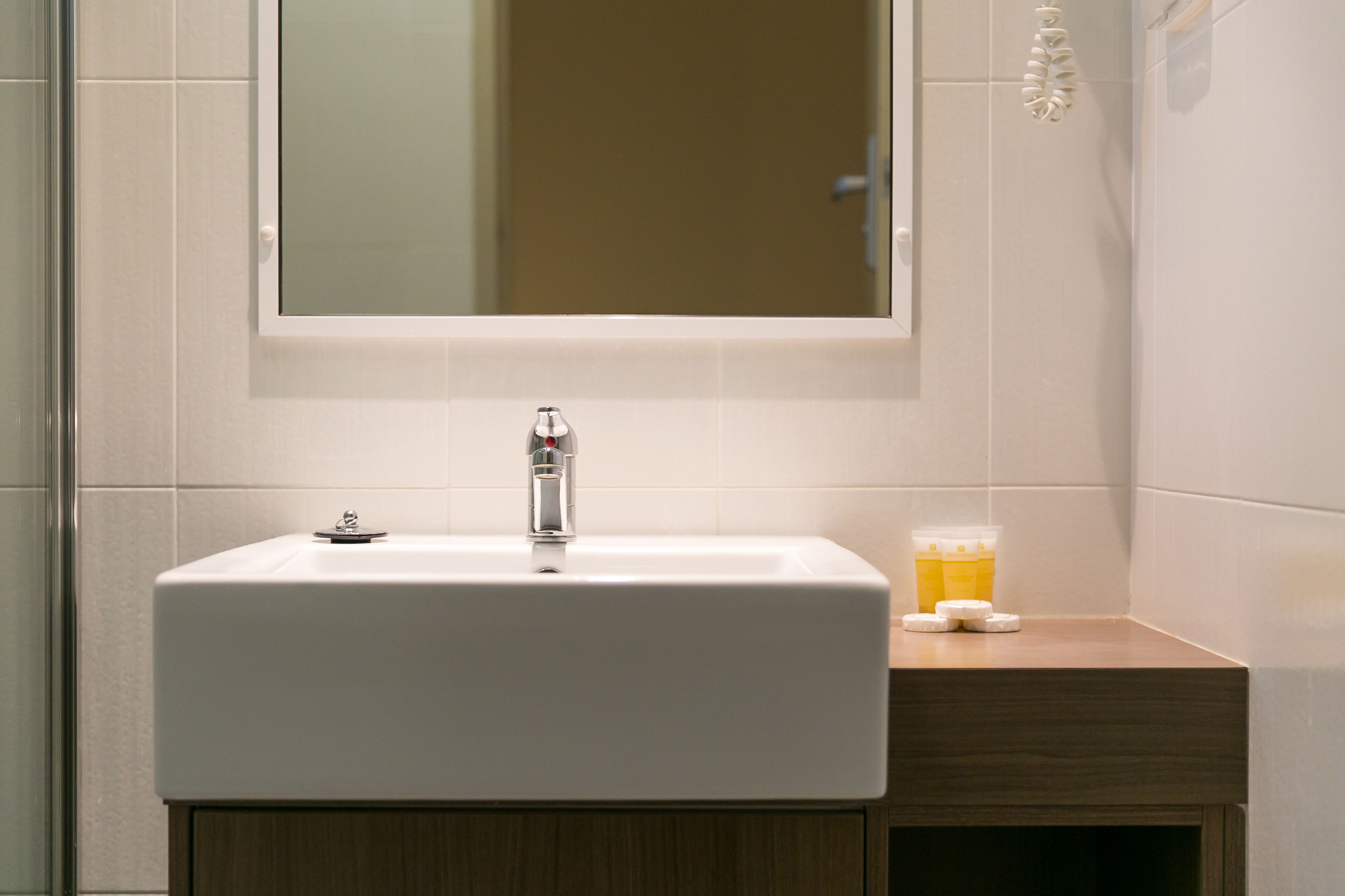 A bathroom with a white sink, a mirror above it, and a wooden cabinet below.