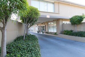 Un edificio con una marquesina, vegetación y un cartel que indica una restricción de altura de 2,4 metros.