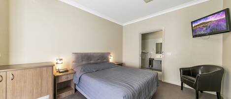A bedroom with a bed, a desk, a chair, a television, and a bathroom.