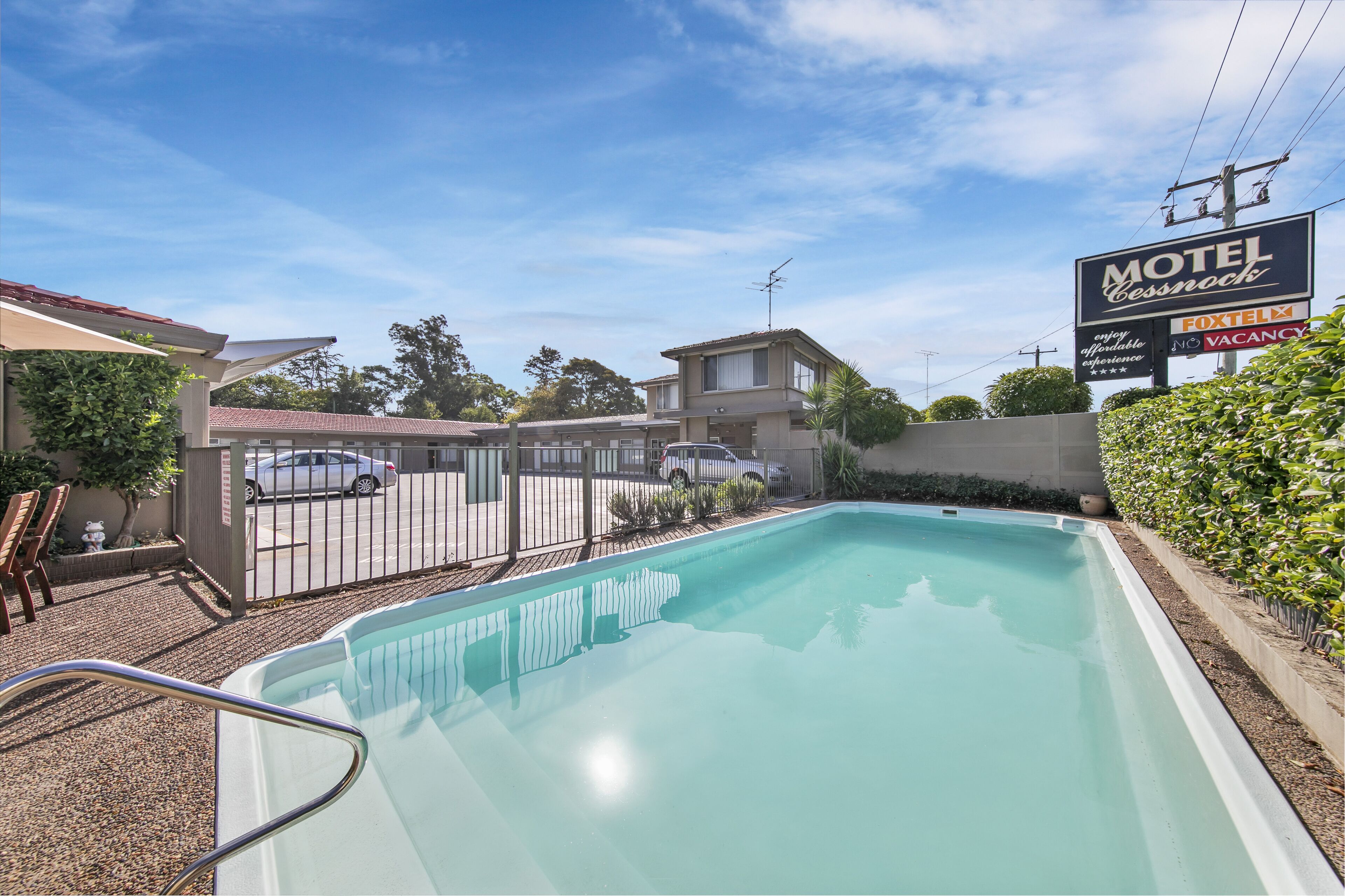 Um motel com piscina, área de estacionamento cercada e um aviso de quartos indisponíveis.