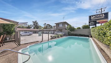Um motel com piscina, área de estacionamento cercada e um aviso de quartos indisponíveis.