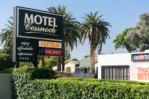 Placa de motel com sinal FoxTelX e aviso de quartos disponíveis.