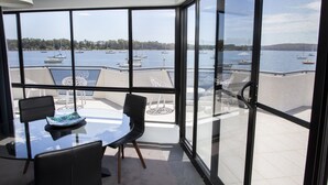 A modern room with a glass wall overlooking a marina with boats. - The Esplanade (Batemans Bay)