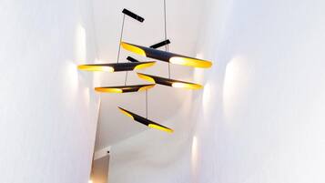 Una escalera de diseño moderno, con barandilla a ambos lados y una lámpara original en la parte superior.