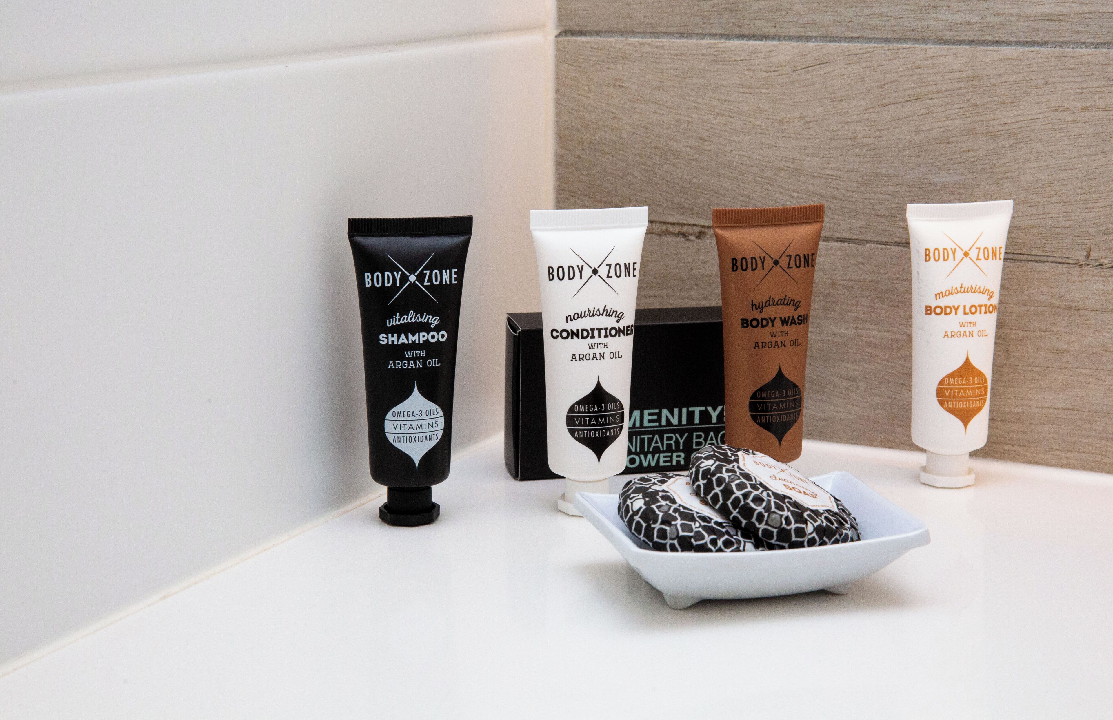 A selection of BODY ZONE personal care products including shampoo, conditioner, body wash, and lotion.