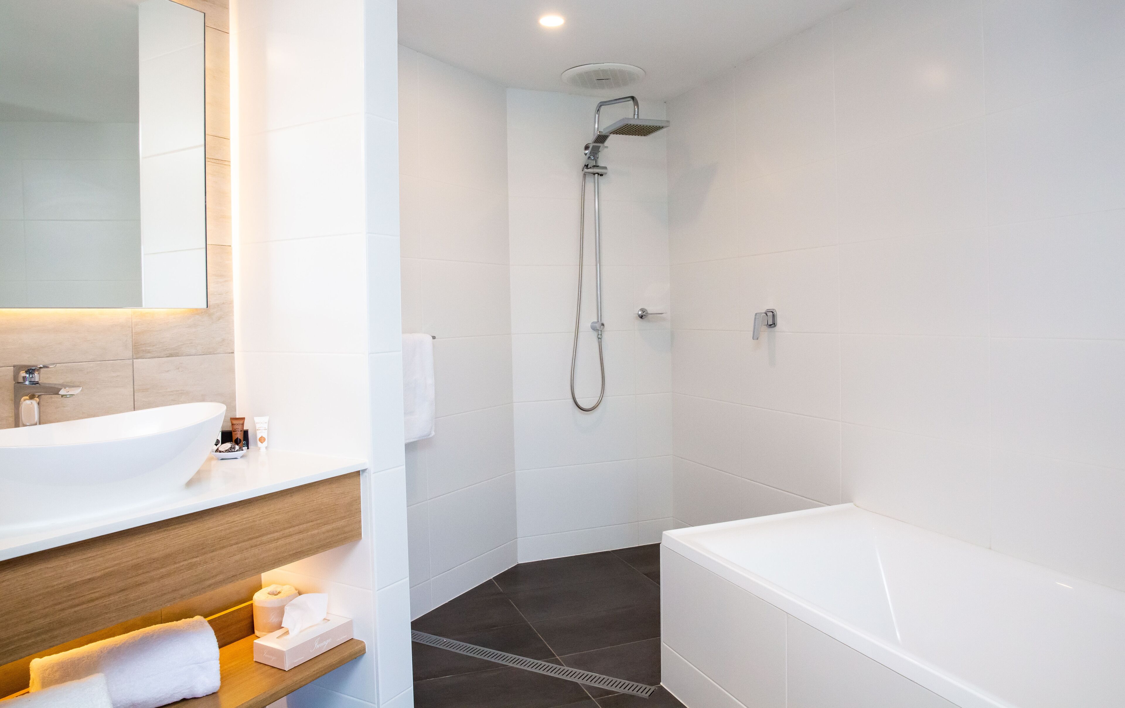 Un baño moderno con lavamanos, tocador y bañera blancos.