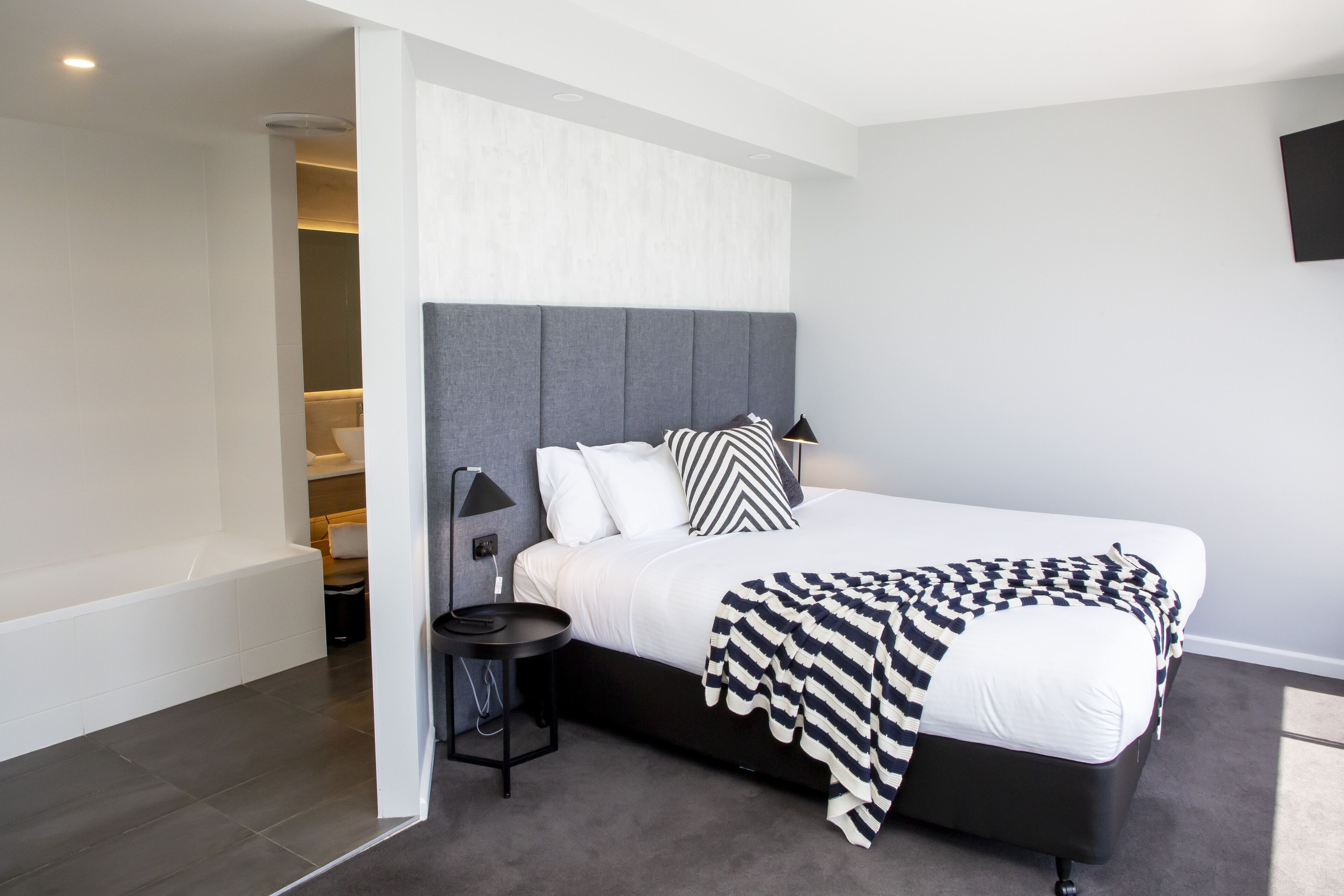 Une chambre à coucher moderne avec un grand lit, une table de chevet et un banc intégré.
