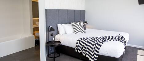 Une chambre à coucher moderne avec un grand lit, une table de chevet et un banc intégré.