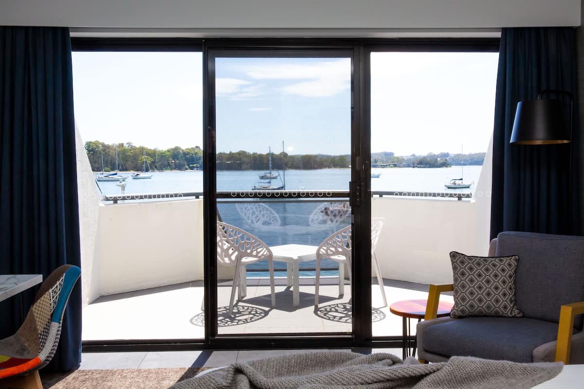 A balcony with a view of the water, a table, chairs, and a sofa.