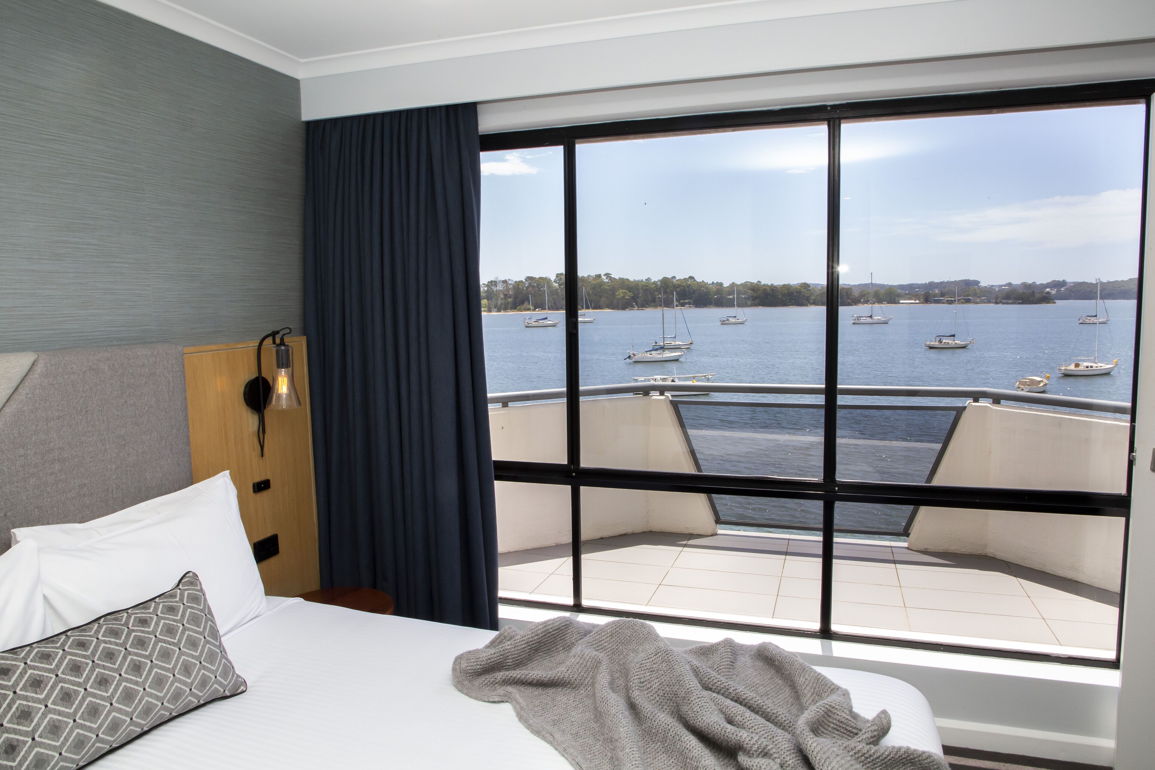 A hotel room with a large window offering a view of the sea and boats.