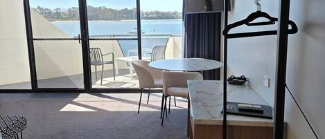 Una habitación de hotel moderna con balcón, zona de comedor y espacio de estar.