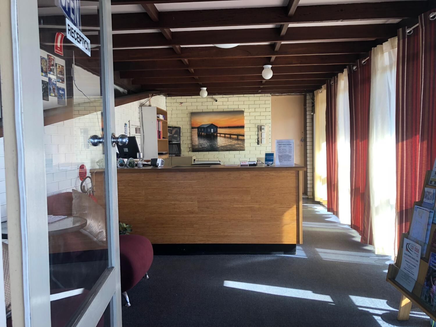 A reception area with a wooden counter, a reception desk, a brick wall, and a window with curtains.