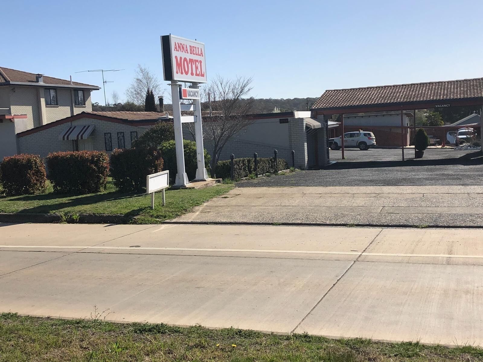 Un motel appelé « Anna Bella Motel », avec une enseigne, un parking et un bâtiment doté d’un toit en tuiles.