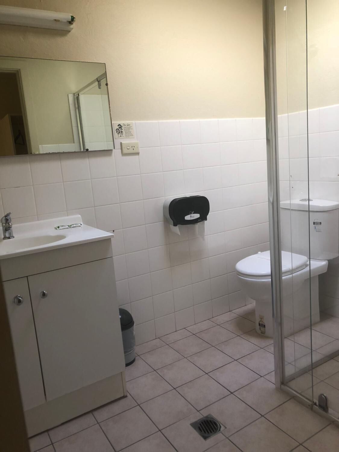 Un baño con lavamanos blanco, espejo, inodoro y cabina de ducha de vidrio.