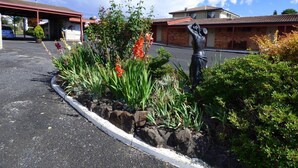 A parking lot with a garden bed, a statue, and a building with a red roof.